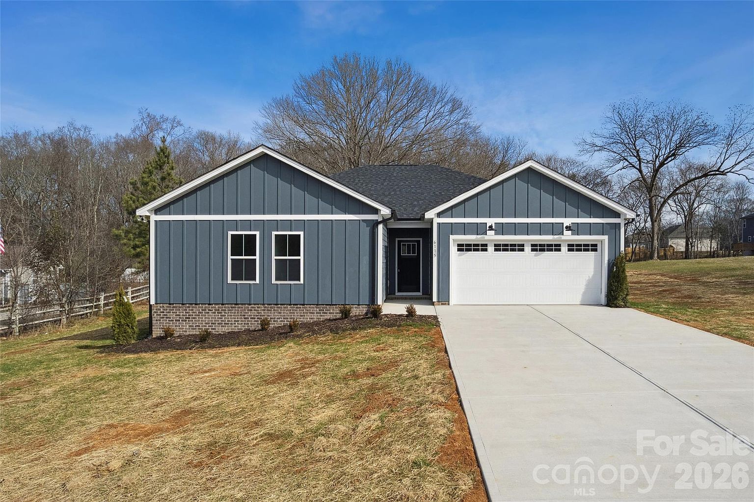 Front view of TrueNest home with blue-gray siding, covered entry porch, and attached two-car garage on a quiet Harrisburg street