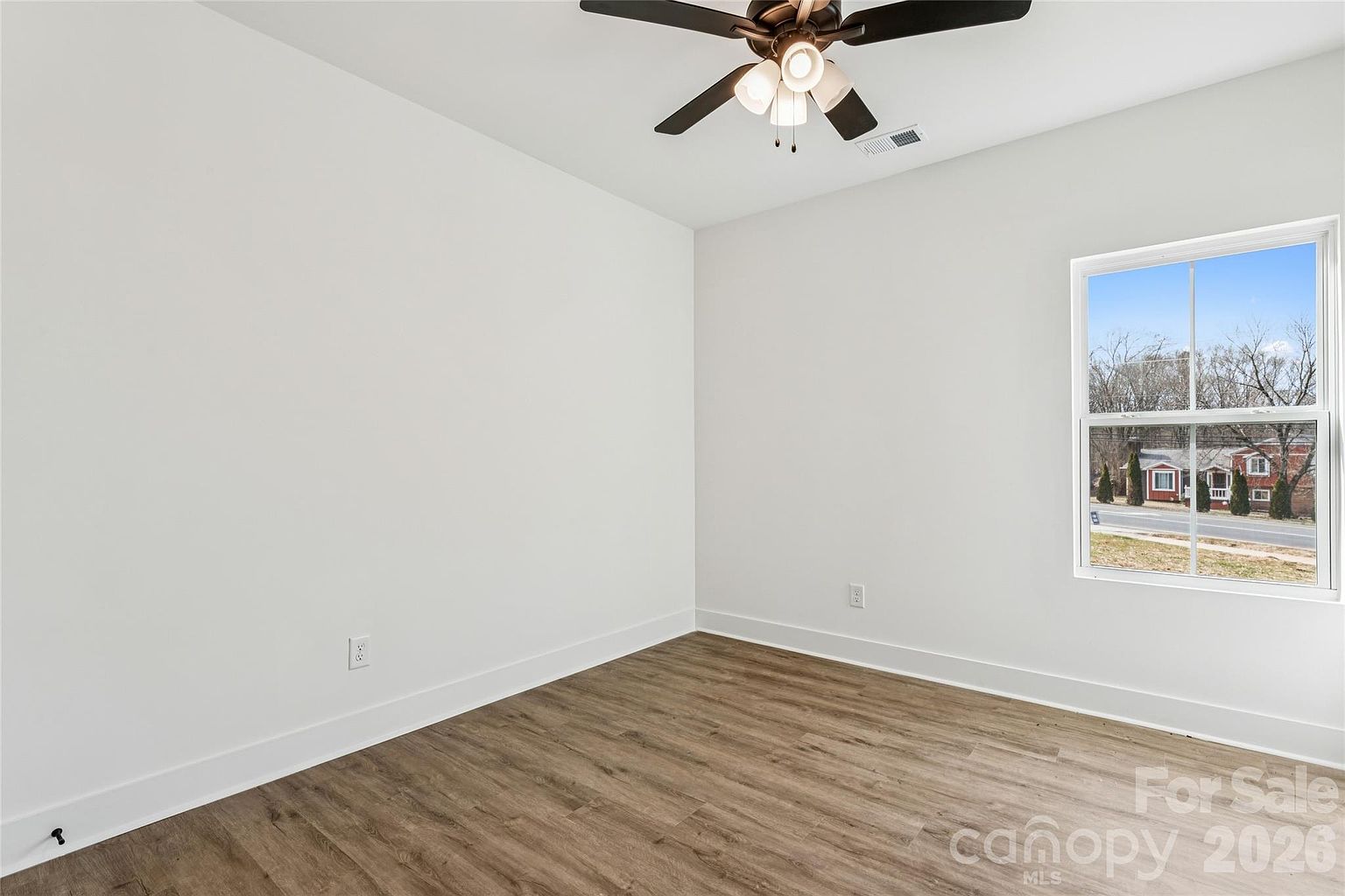 Bedroom with ceiling fan and a large window letting in sunlight with a view of the quiet neighborhood